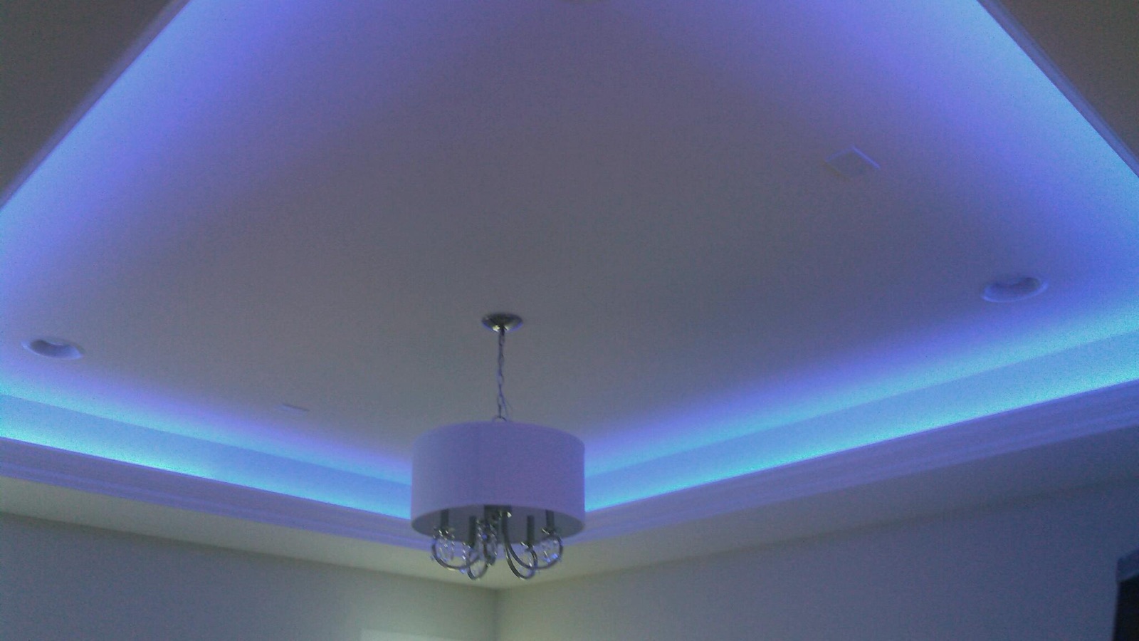 Tray ceiling washed in blue LED light over a chandelier