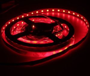 Red illuminated RGB LED strip reel glowing in dark background